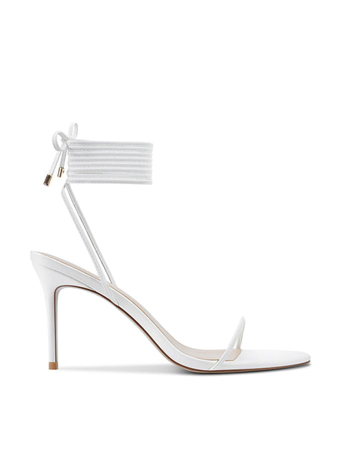 FEMME LA 3.0 Barely There Lace Up Heel in white — side profile showing thin toe strap, slim stiletto heel, and multi-wrap lace-up ankle cuff with gold aglets