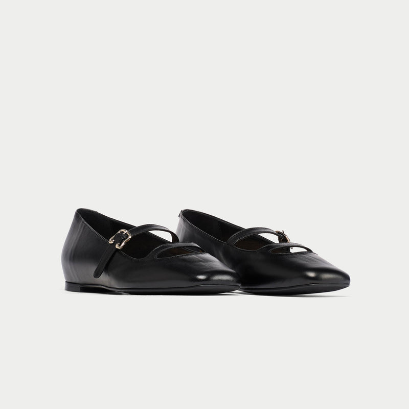 Pair of black leather shoes with buckles on a light gray background