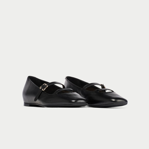 Pair of black leather shoes with buckles on a light gray background