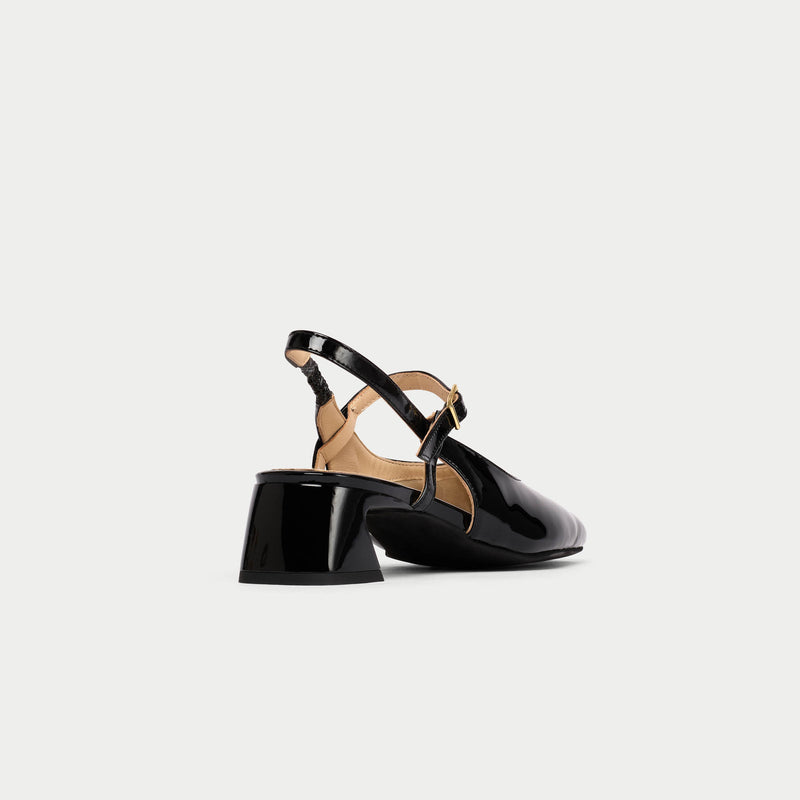 Black low-heeled shoes with a strap on a light gray background