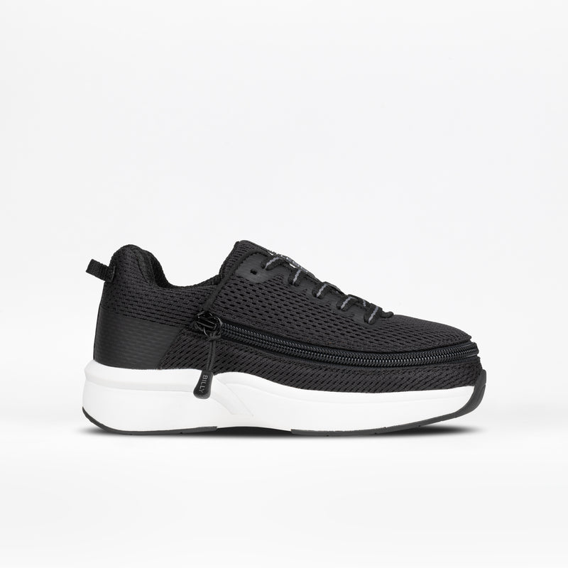 A side profile of the black Kids' Limitless sneaker by BILLY Footwear, featuring mesh fabric, black laces, and a thick white sole, is displayed against a plain white background.