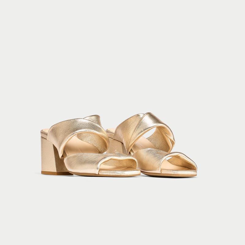 Pair of gold high-heeled shoes on a light gray background