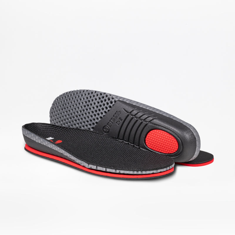 A pair of Women's Black Leather BILLY Comfort Plush insoles by BILLY Footwear: one lies flat with a textured top, while the other is propped up to show a patterned gray underside and a red heel cushion.